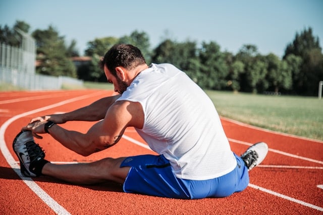 Hardloper die zijn kuit stretcht in de ochtendzon