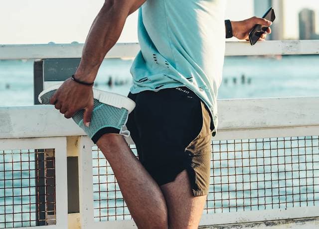 Runner doing a dynamic warm-up exercise along a park path