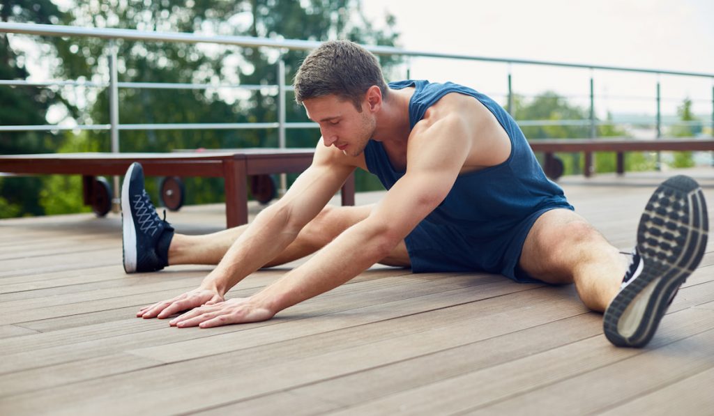 man stretching outdoor in wide leg forward bend position