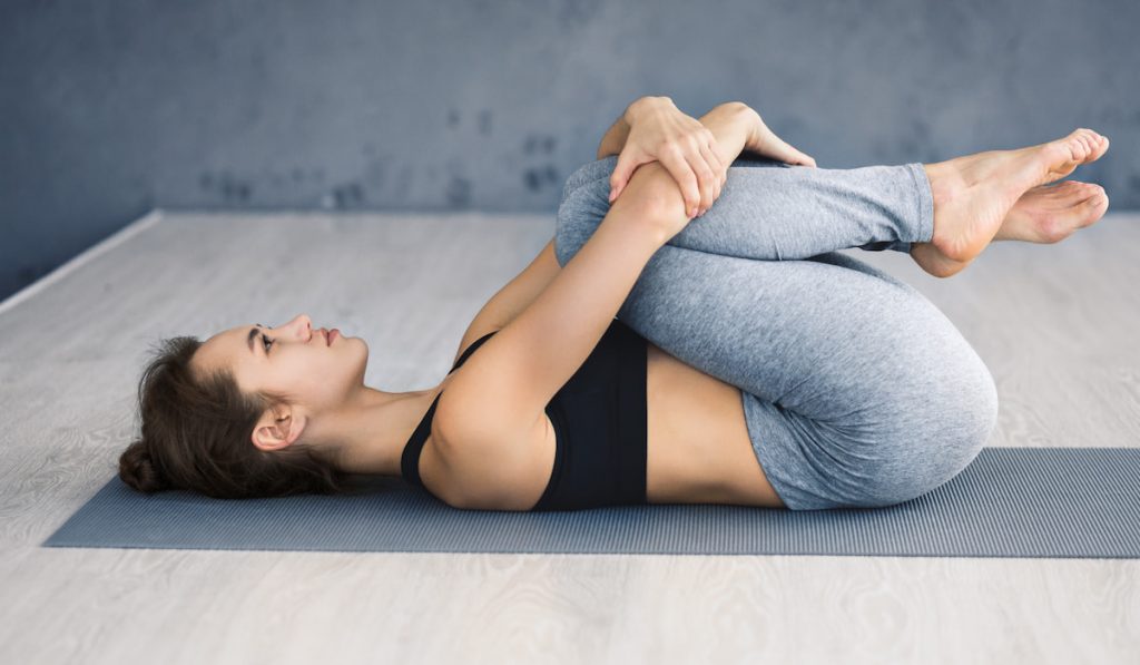 woman stretching knees to chest pose